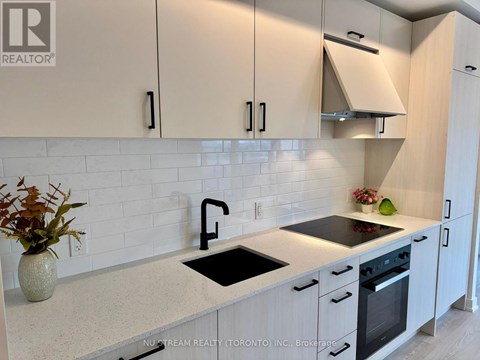 A kitchen with white cabinets and a wooden floor.