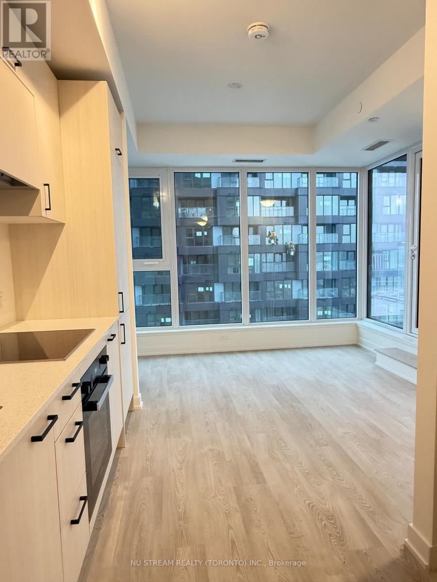 A kitchen with white cabinets and a view of a cityscape through the windows.