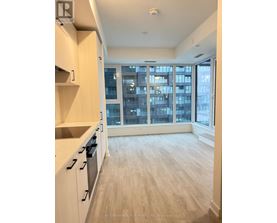 A kitchen with white cabinets and a view of a cityscape through the windows.