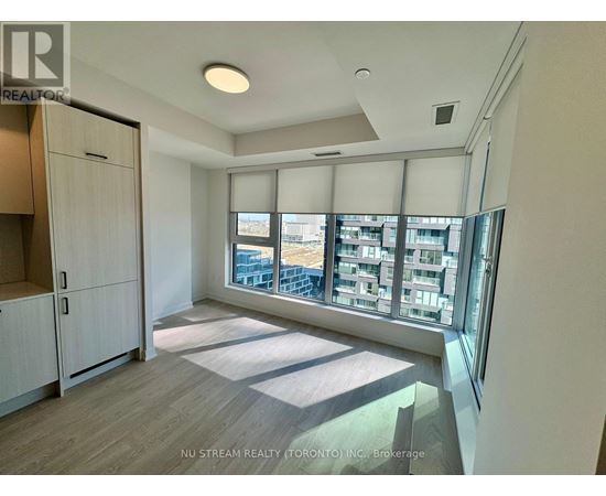 A kitchen with white cabinets and a view of a cityscape through the windows.