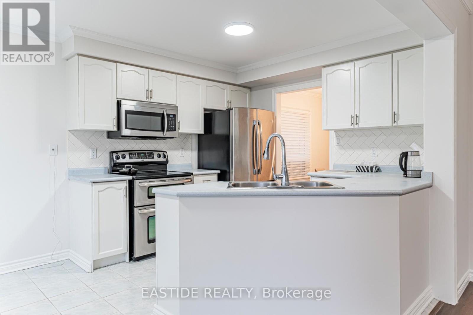 A white kitchen with a sink and a refrigerator.
