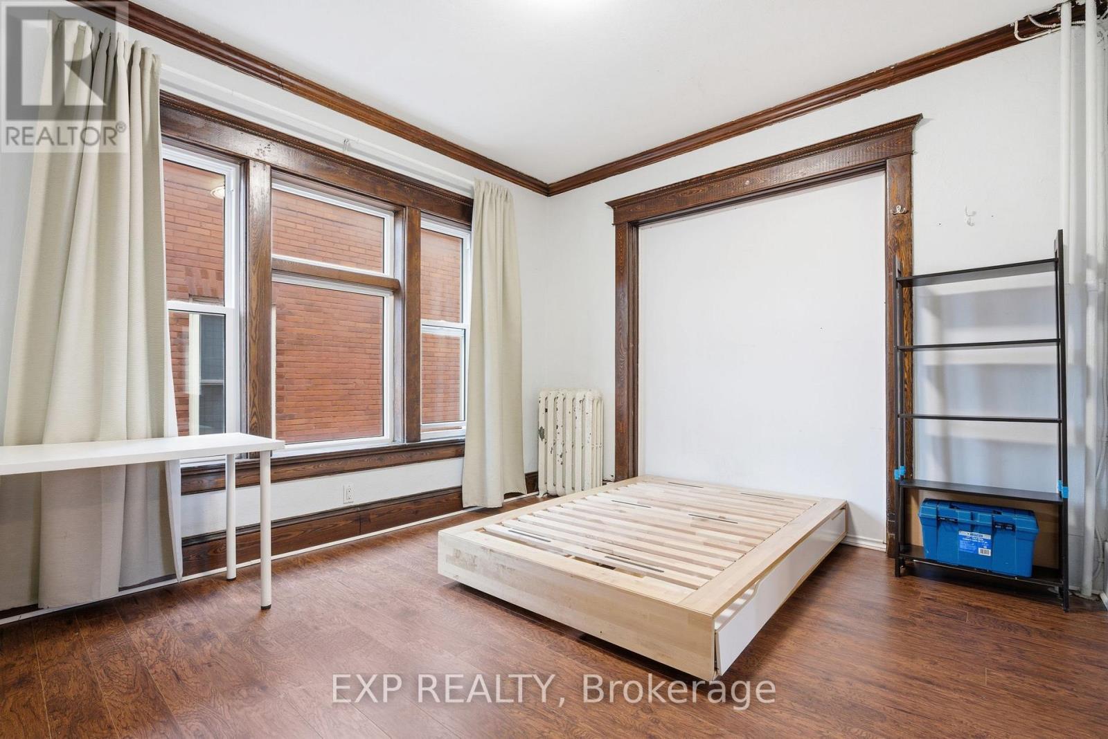 A bedroom with a bed, a window with curtains, and a radiator.
