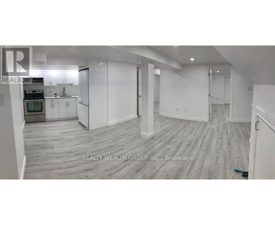 A spacious room with a kitchen area and a dining table.