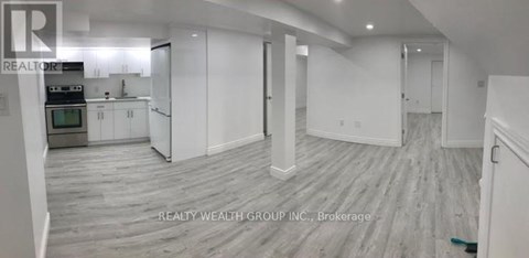 A spacious room with a kitchen area and a dining table.