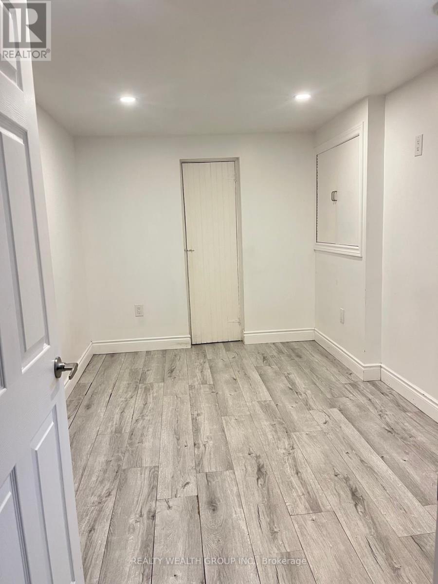 A room with a white door and grey wood flooring.