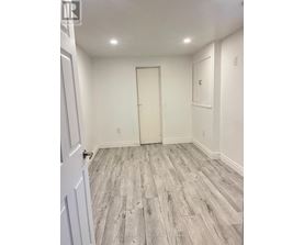 A room with a white door and grey wood flooring.