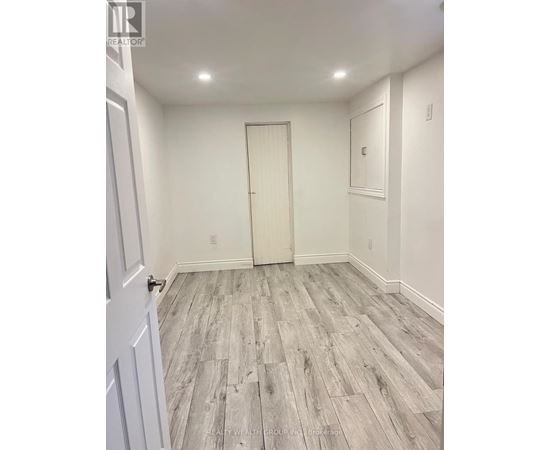 A room with a white door and grey wood flooring.