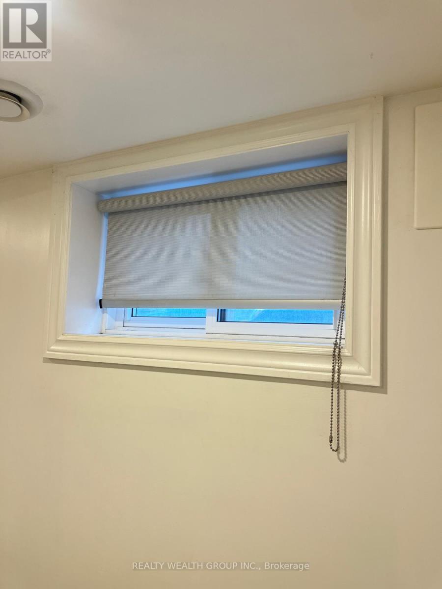 A window with white blinds and a curtain is in a white room.