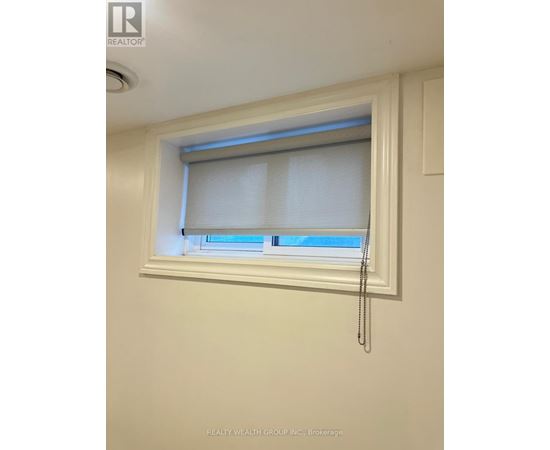 A window with white blinds and a curtain is in a white room.