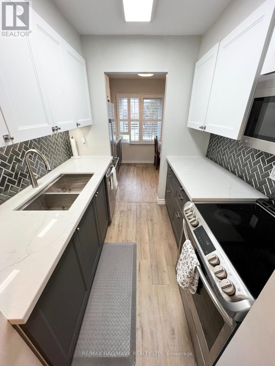 A kitchen with white cabinets and a black and white tiled backsplash.