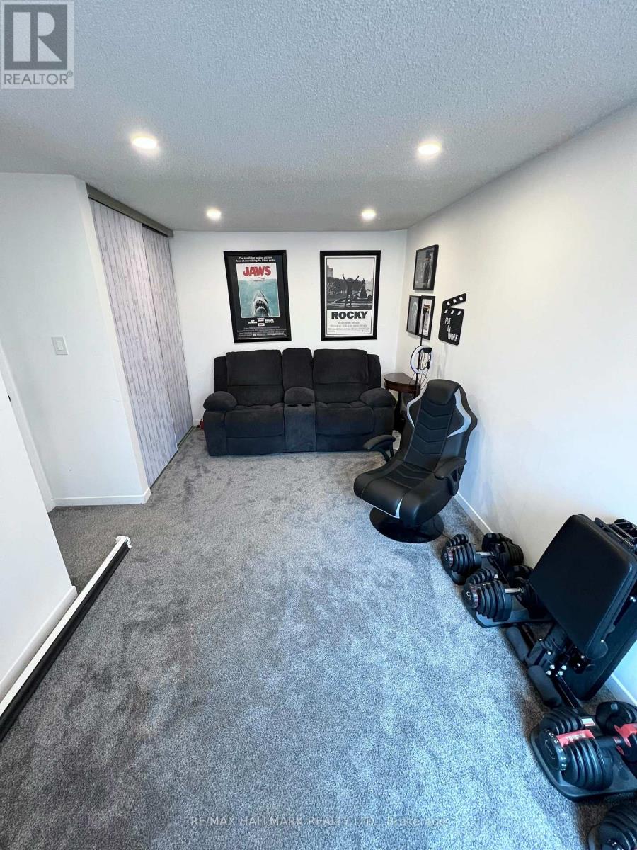 A living room with a grey carpet and a black sofa.