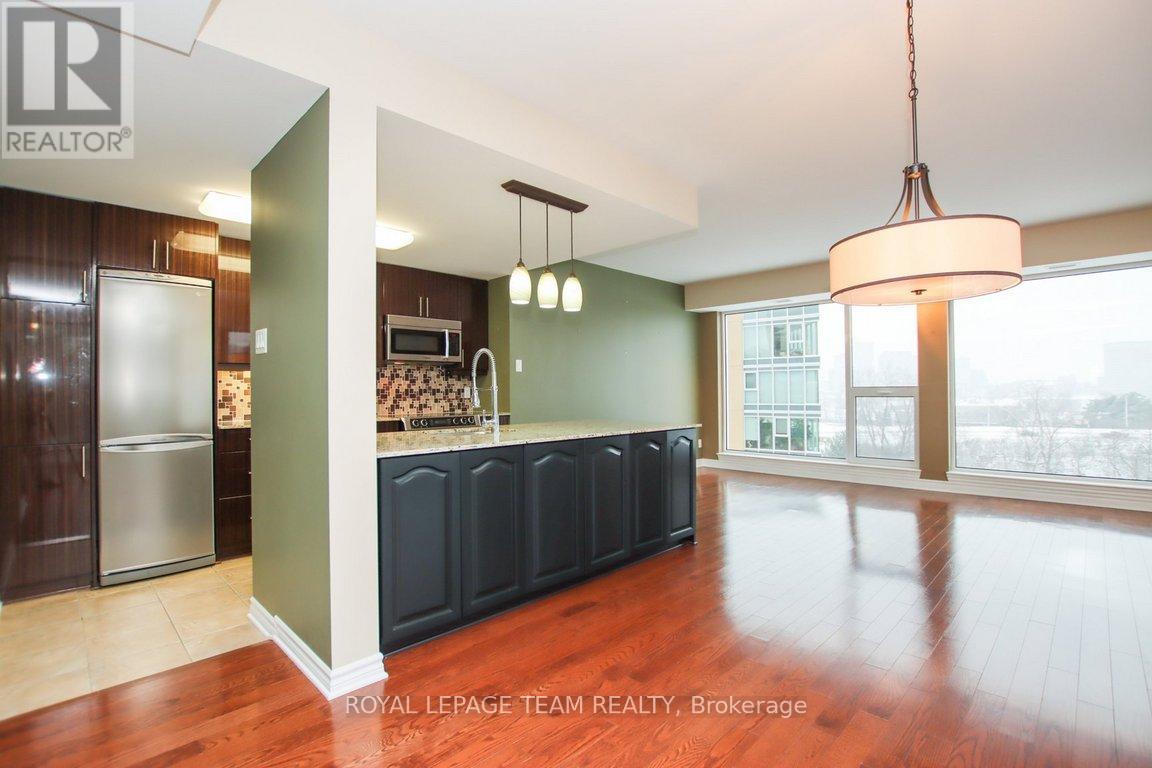 A well lit kitchen with dark wood cabinets and a refrigerator.
