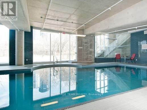 A swimming pool inside a building with a glass wall.