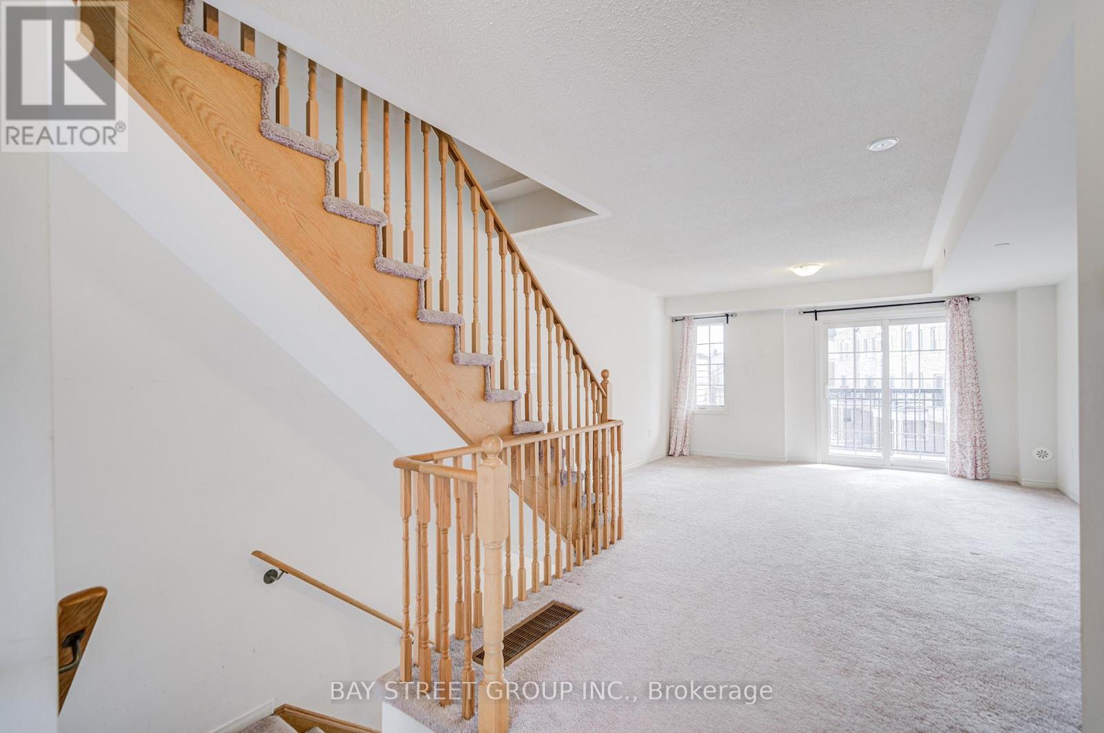 A spacious room with a wooden staircase and a large window.