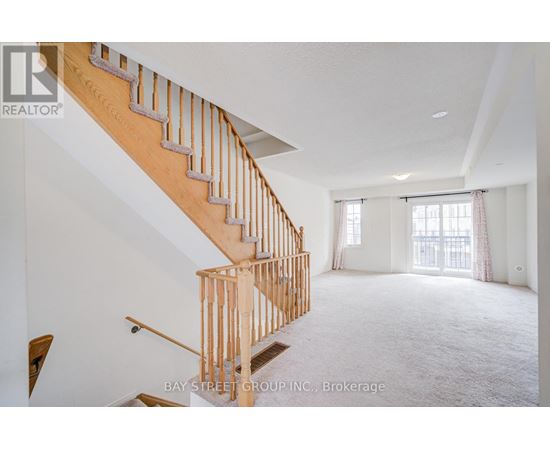 A spacious room with a wooden staircase and a large window.