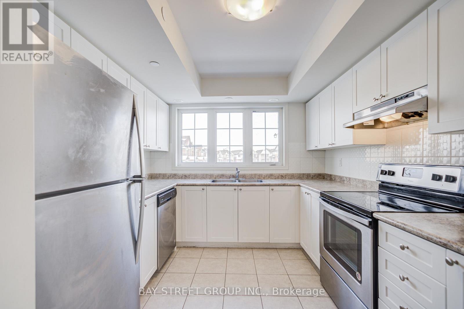 A kitchen with white cabinets and a stainless steel refrigerator.