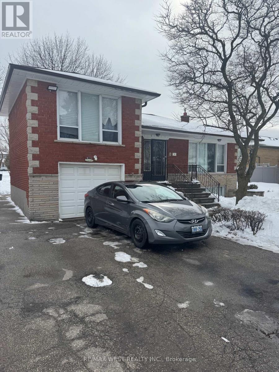 A grey car is parked in front of a red brick house.