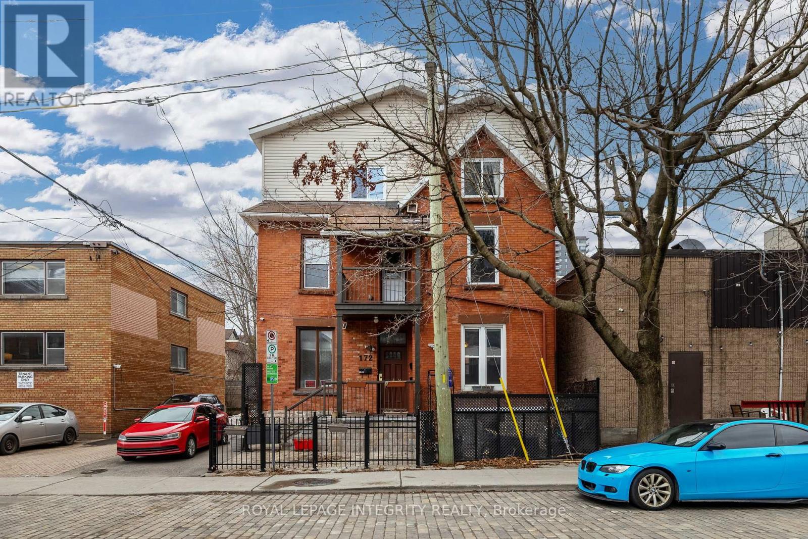 A red brick house with a blue car parked in front.