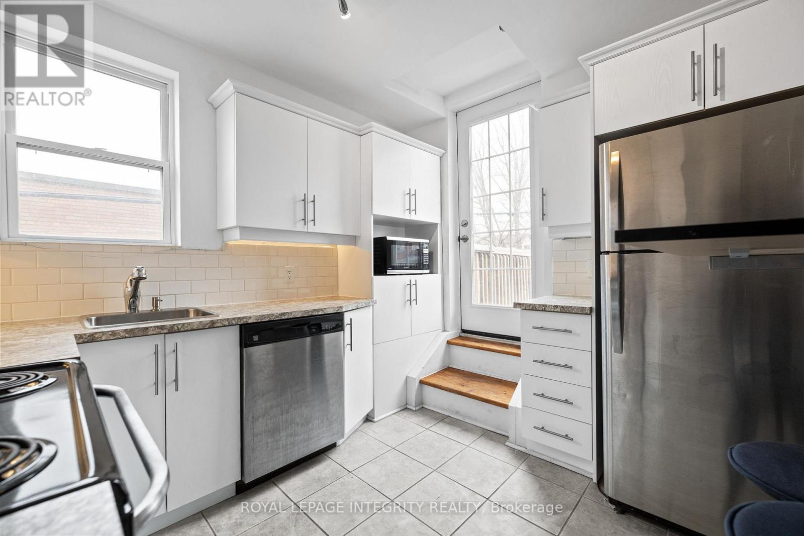 A kitchen with white cabinets and a stainless steel refrigerator.