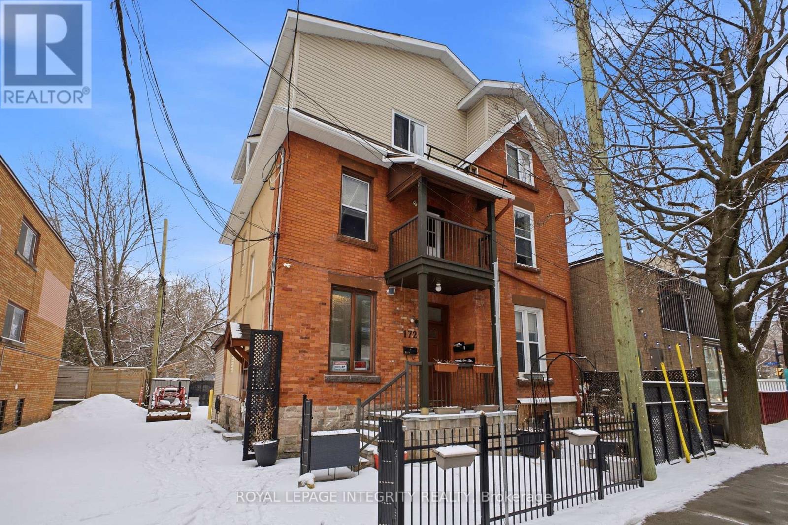 A house with a snow-covered front yard and a black fence.