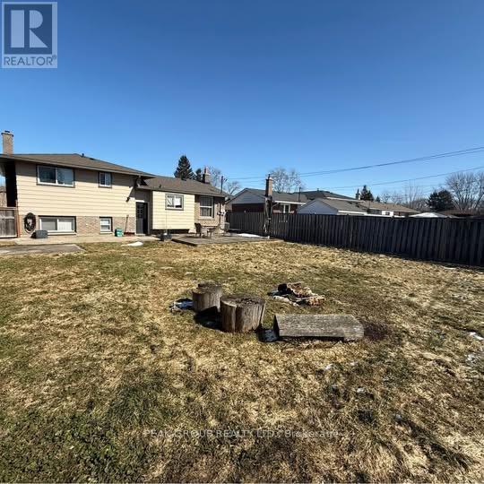 A backyard with a fence and a few pieces of wood on the grass.