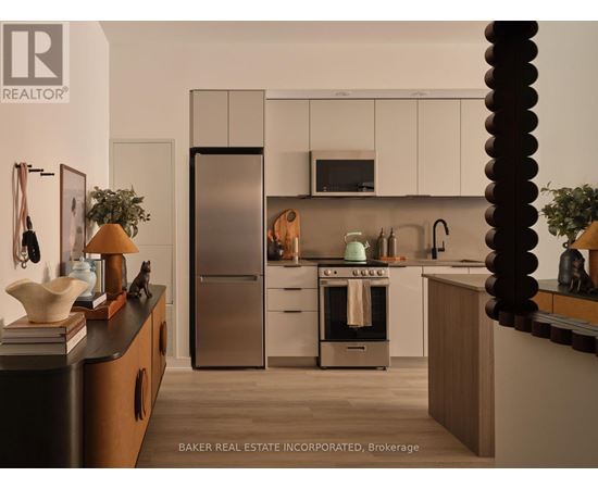 A modern kitchen with a refrigerator, oven, and microwave.