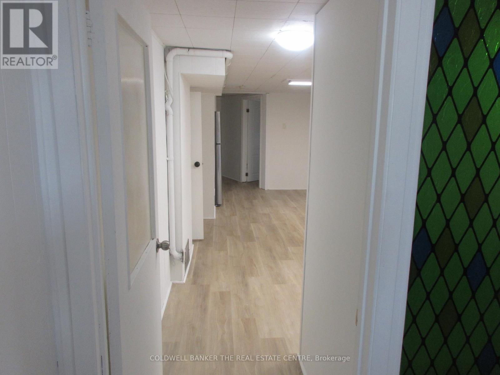 A hallway with white walls and a wooden floor.