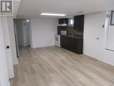 A kitchen with black cabinets and a white fridge.