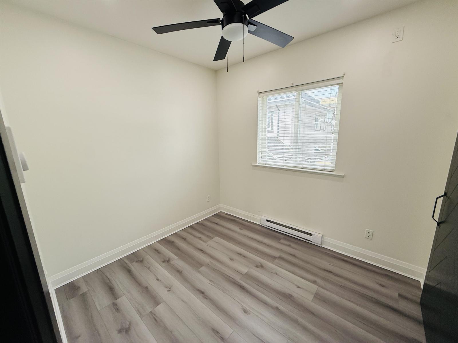 A room with a ceiling fan and a window with blinds.