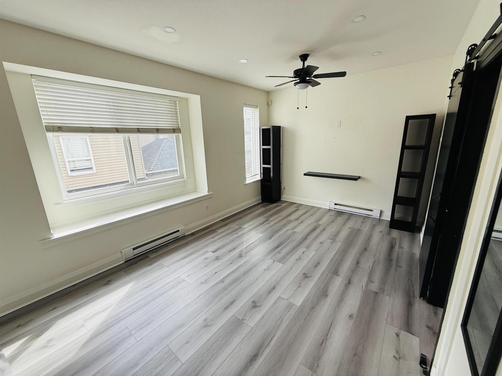 A room with a ceiling fan and wooden flooring.