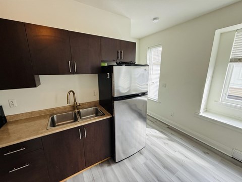 A kitchen with dark brown cabinets and a stainless steel refrigerator.
