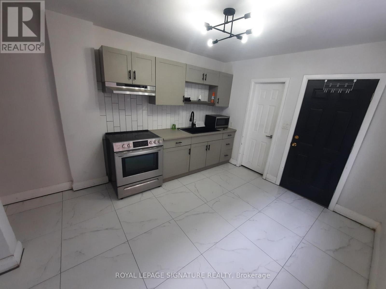 A kitchen with a stove top oven, microwave, and a refrigerator.
