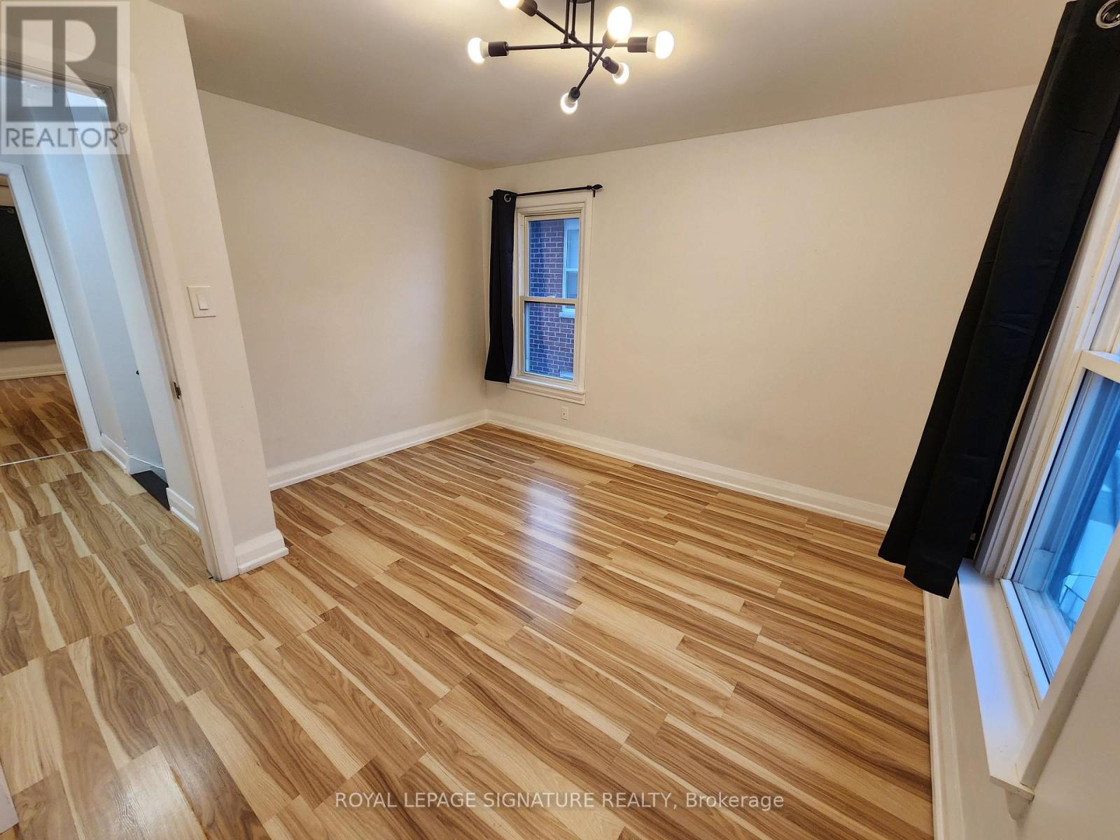 A room with wooden flooring and a window with a black curtain.