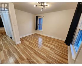 A room with wooden flooring and a window with a black curtain.