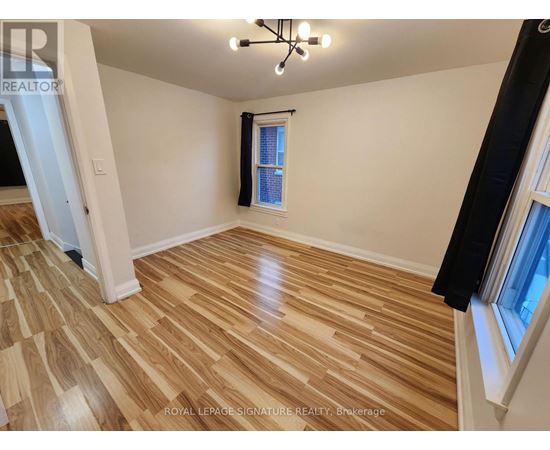 A room with wooden flooring and a window with a black curtain.
