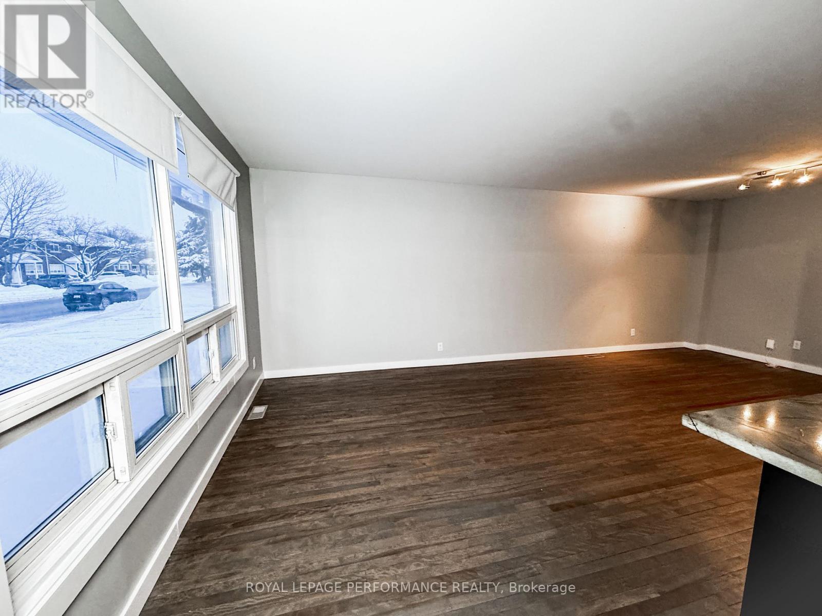 A room with a large window and wooden flooring.