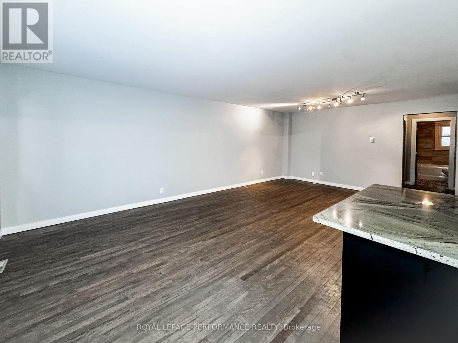 A spacious room with wooden flooring and a marble countertop.