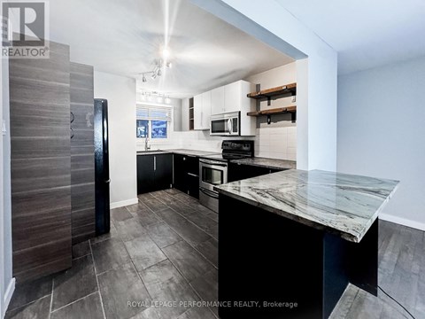 A modern kitchen with a marble countertop and a refrigerator with a wooden door.