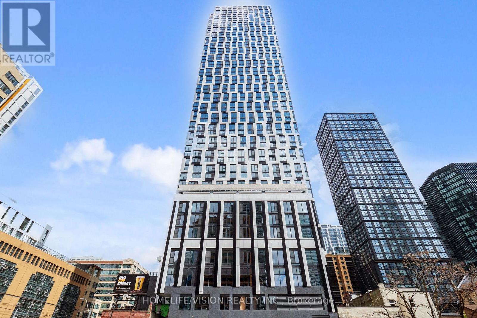 A tall building with many windows stands in front of other buildings.