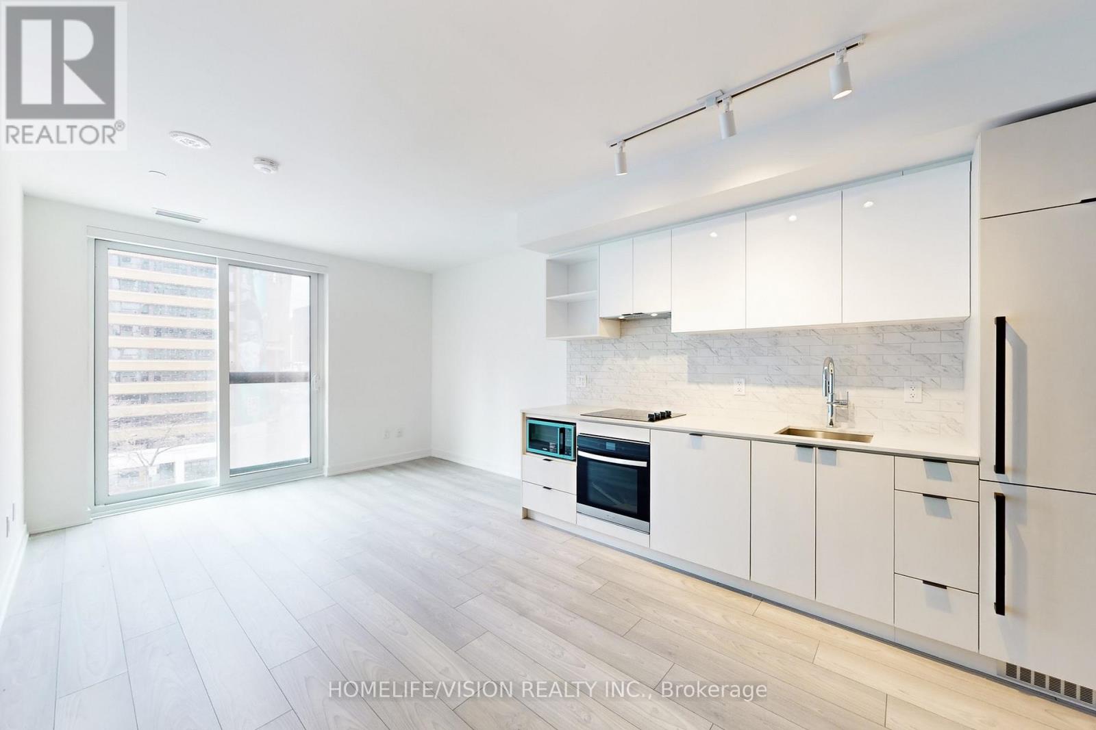 A modern kitchen with white cabinets and a marble backsplash.