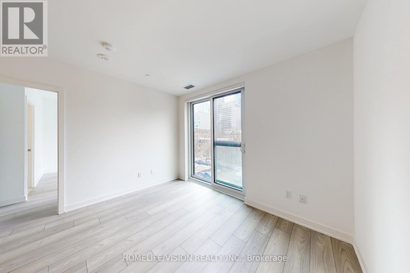 A spacious, empty room with a sliding glass door leading to a balcony.