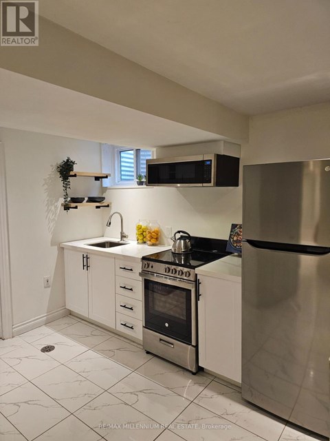 A kitchen with white cabinets and a stainless steel refrigerator.