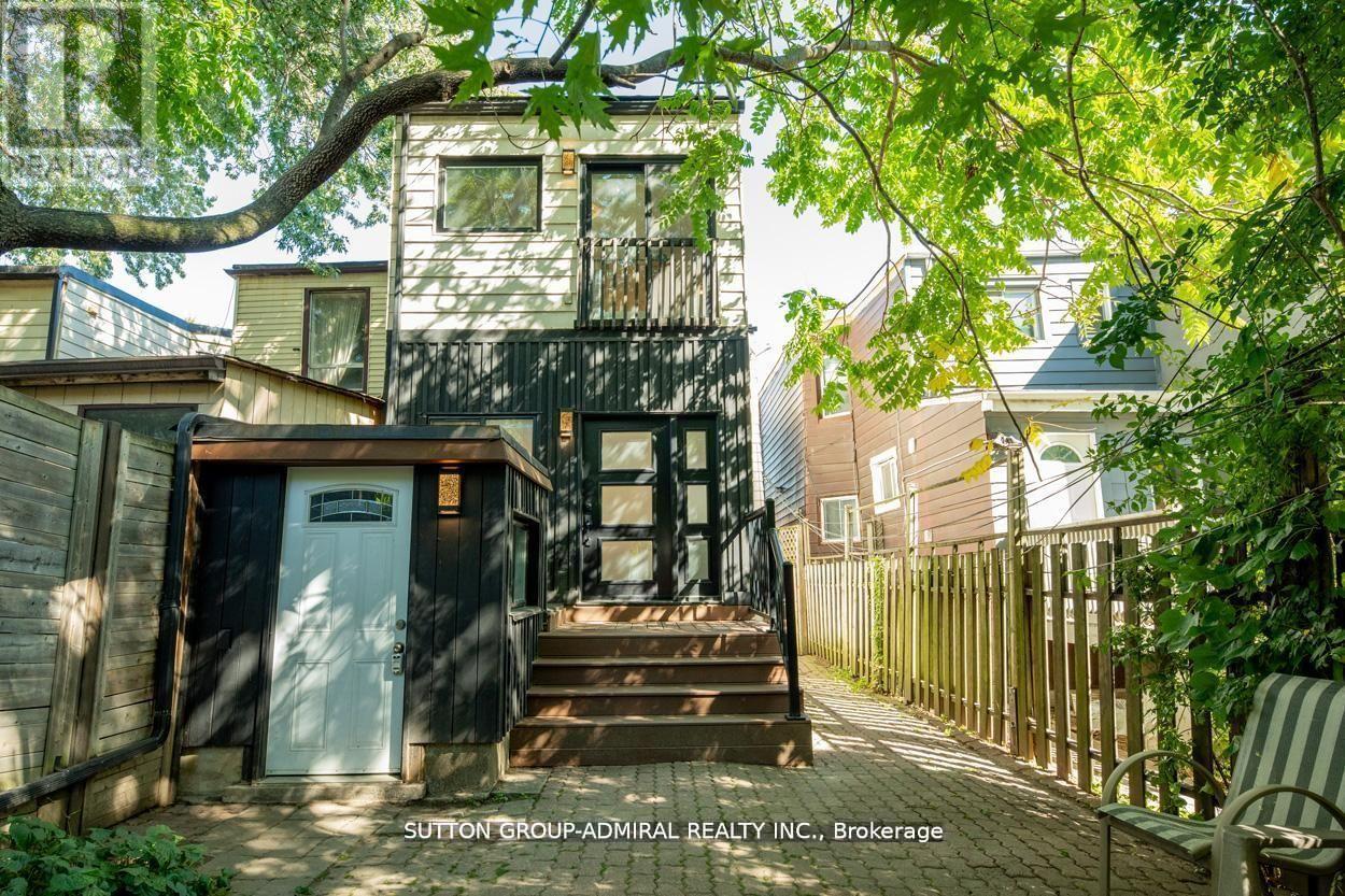 A tree branch is in the foreground of a photo showing a house and a sign that says Sutton Group Admiral Realty Inc Brokerage.