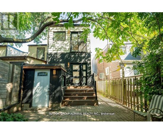 A tree branch is in the foreground of a photo showing a house and a sign that says Sutton Group Admiral Realty Inc Brokerage.