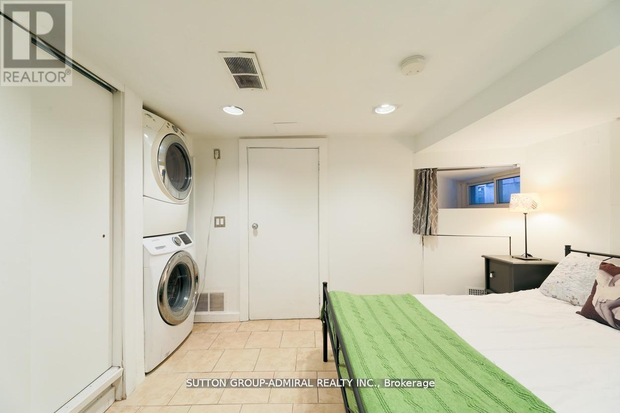 A bedroom with a washing machine in the corner.
