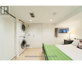 A bedroom with a washing machine in the corner.