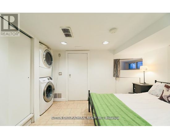 A bedroom with a washing machine in the corner.