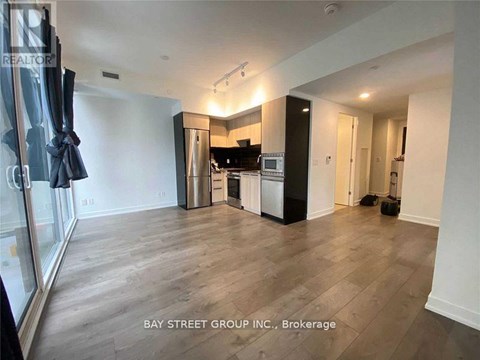 A spacious living room with a kitchen area in the background.