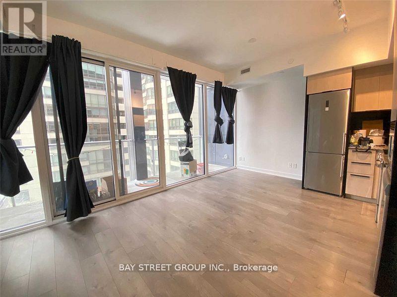 A spacious room with a kitchen area and a view of the city through large windows.