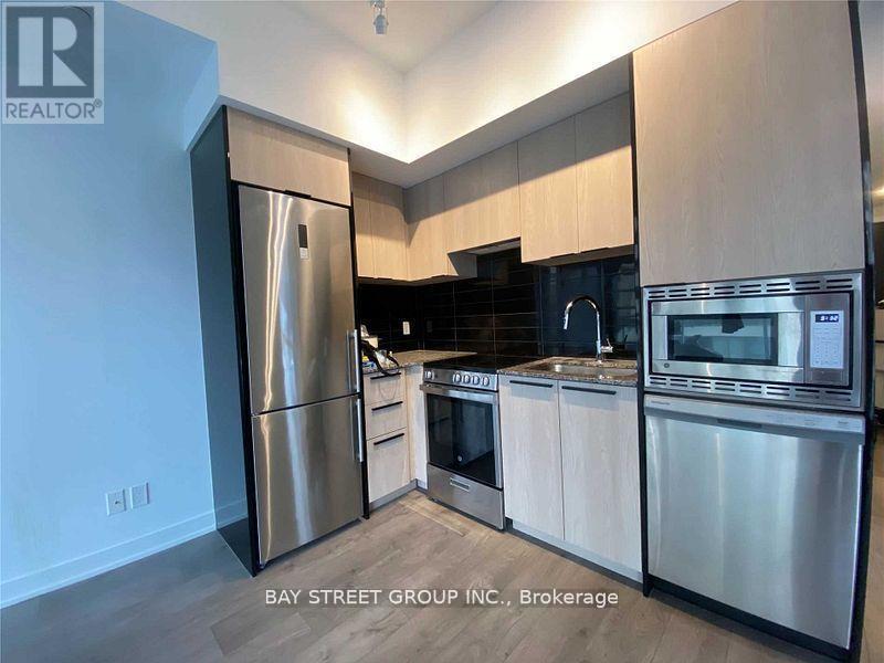 A modern kitchen with stainless steel appliances and wooden cabinets.